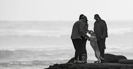 3 gioiose con un cane, con sfondo il mare.